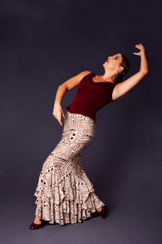 Beautiful female Flamenco dancer doing a typical line pose, wearing modern attire. Spanish woman dancing Flamenco in brown clothes with polka dots, isolated.