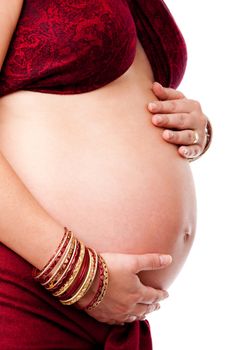 Pregnant woman holding her belly, dressed in red and gold with red bracelets on her arm, isolated.