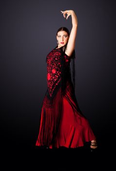 Beautiful female Spanish Flamenco dancer doing a typical line pose, wearing modern attire. Spanish woman dancing Paso Doble in red and black dress clothes, isolated.