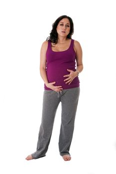 Beautiful pregnant Caucasian brunette woman holding her belly with an uncomfortable expression. Pregnancy contraction pains, isolated.