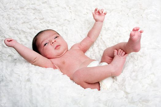 Happy Caucasian Hispanic infant baby falling on soft white cotton cloud with arms and legs in the air.