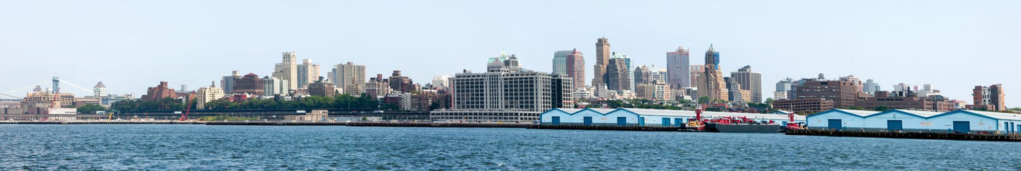 Panoramic view of the landmark skyline of Brooklyn in New York City, showing many apartment and residential buildings including pier and docks used for commercial trade and warehouses.