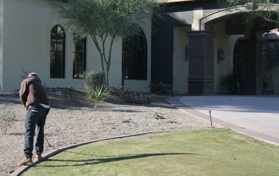 Man cleaning landscaping of a upscale home