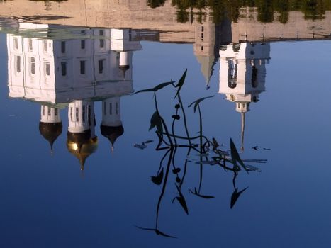 Reflection of the church on the water of Velikaya river.