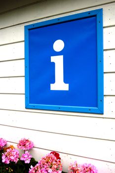 A large sign for an information point, mounted on a wooden clapboard building, with hydrangeas