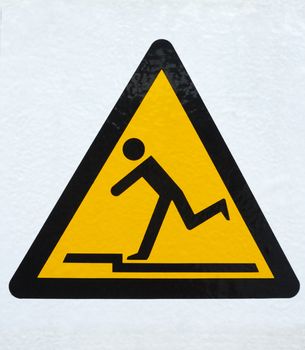 A sign, warning of the danger of tripping on a step. Placed on a slightly textured white background. Clipping path included so it can be extracted on to any other background.