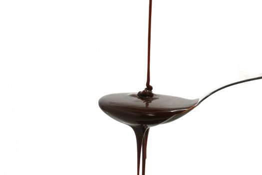chocolate syrup flowing on a silver spoon