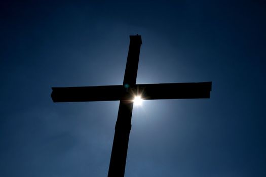 a cross with the sun behind it