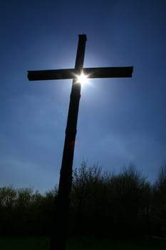 a cross with the sun behind it