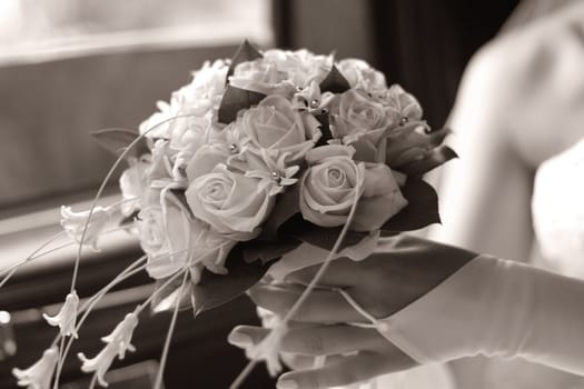 The bride holds a wedding bouquet. b/w+sepia