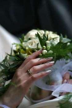 The image of a hand of the bride with a bouquet. The wedding sharp ring, the rest is dim