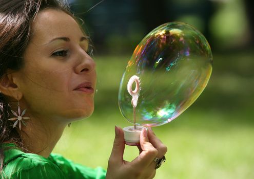 The girl makes big soap bubble in park