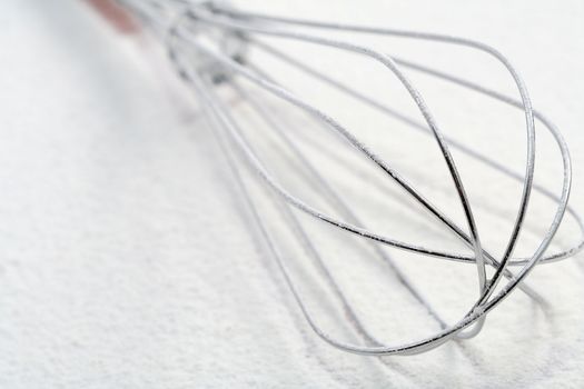 Wire whisk on flour, background 