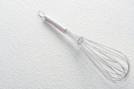 Wire whisk on flour, background 