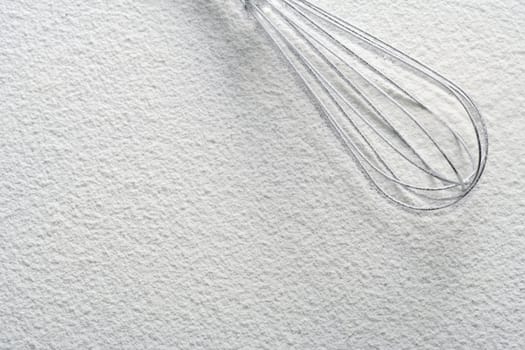 Wire whisk on flour, background 