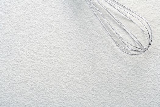 Wire whisk on flour, background 