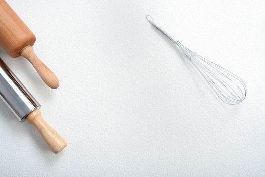 Wire whisk and rolling pin on flour, background 