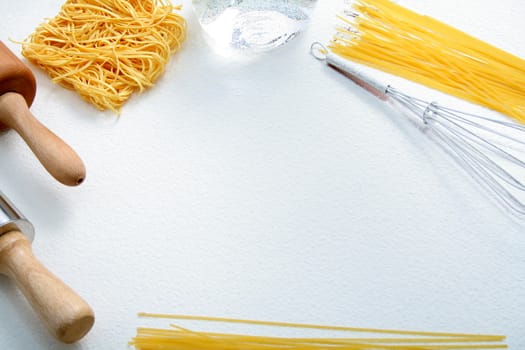 Wire whisk, macaroni and rolling pin on flour, background 