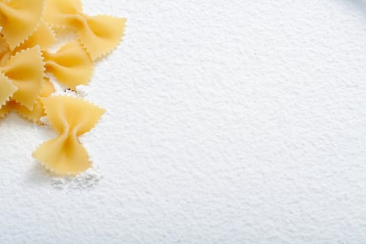 Uncooked macaroni on wheat flour, background