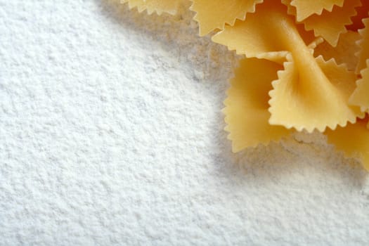 Uncooked macaroni on wheat flour, background