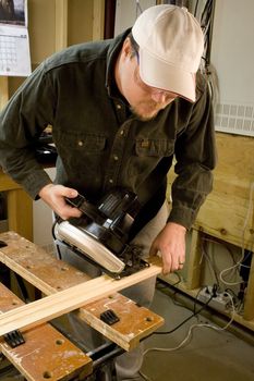 Man in workshop with skillsaw cutting a piece of wood