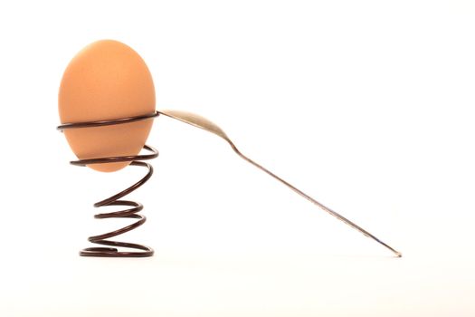 Egg inside spiral eggcup near spoon isolated on white background