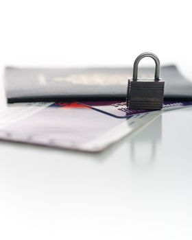 Picture of a Canadian Passport, a credit card, and a plan ticket, with focus on a small padlock, isolated on white.