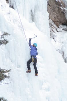 Man ice climbing frozen waterfall
