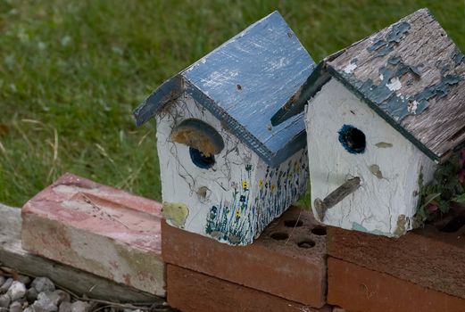 A couple of old bird houses sitting on red bricks.