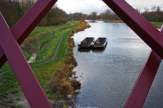 View through iron bridge on landscape with boats