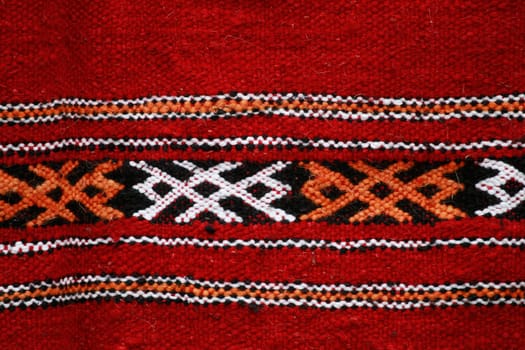 Red ethnographical handmade blanket with color pattern.