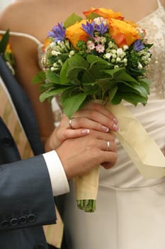 The bride and the groom hold a beautiful wedding bouquet in hands