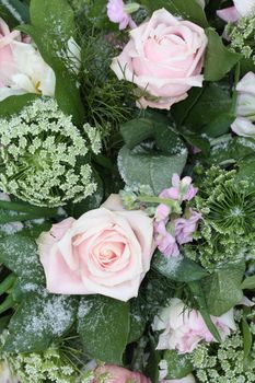 A pink rose flower arrangement with matching flowers in the snow