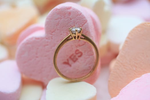 Solitaire diamond engagement ring on valentine candy heart with text �es"