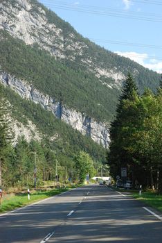 Highway in Austrian Alps with mountain and pines beside the road