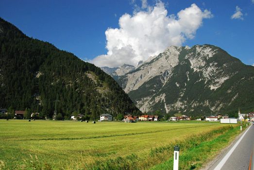 Highway in Austrian Alps with mountain and pines beside the road