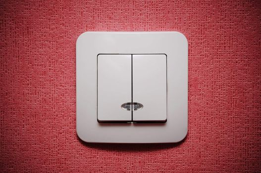 Double light switch against red wall closeup