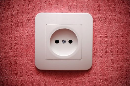 Electric plug connector (outlet) on red wall