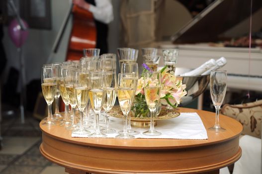 Many champagne glasses in fine restaurant on a table with live music on background