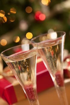 Sparkling Champagne Flutes and Gifts in Front of Decorations and Lights.