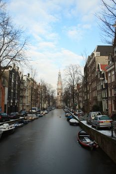 Winter panorama of Amsterdam city in Netherlands with frozen canal and tower