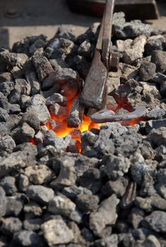 medieval craftsman blacksmith warming a piece of iron in the fire