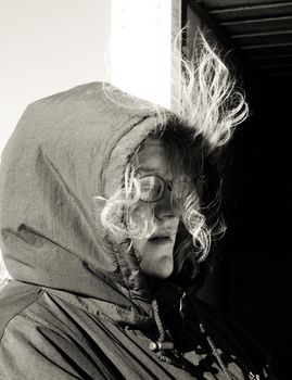 Blond girl bundled up against the bitter cold in heavy coat with hair blowing in the winter wind