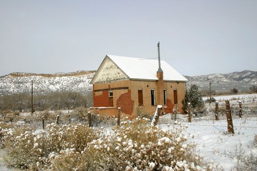 Old, historic adobe one-room schoolhouse in snow