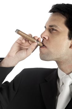 A good looking young business man somking a cigar, in a studio shot.