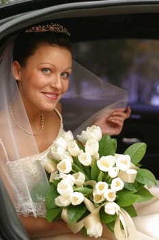 Beautiful the bride with a bouquet in the automobile
