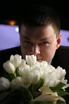 The groom with a bouquet from white tulips 