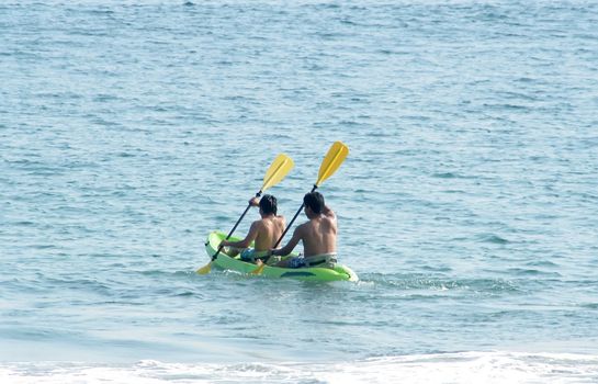 Two men rowing in sea kayak in ocean