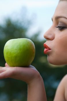 Girl with apple on sunset on green background