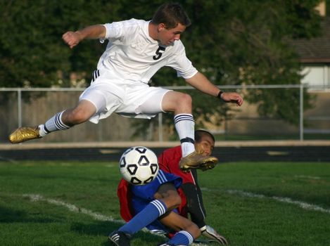 Player kicks soccer ball over goalie and into net for a score